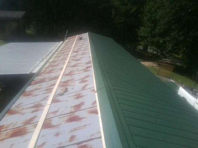 Old rusted panels beside newly installed green metal roofing — Wind Damage Roof Repair by Roofing Brothers in Hewitt