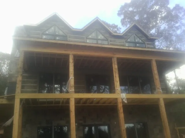 Dormers and porch framing on a large log home under construction — Roof Coating work by our crew in Hewitt